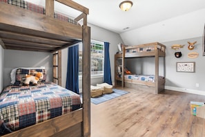 Ein Zimmer mit Etagenbetten, einem Vorhangfenster, einem Teppich und Wandverzierungen mit Tierköpfen.