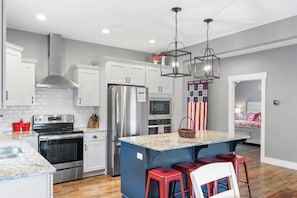 A modern kitchen with stainless steel appliances, granite countertops, and a central island with bar stools.