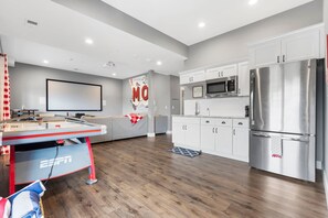 A modern kitchen with white cabinets, stainless steel appliances, and a wooden floor.