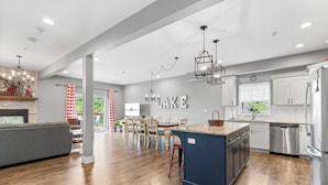 A modern kitchen with a central island, stainless steel appliances, and a dining area with a chandelier. - Scenic Lake Views, Inviting Community Pool, Free Daily Attraction Tickets & Air Hockey! (Branson)