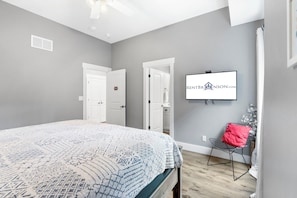A bedroom with a bed, a television mounted on the wall, and a chair.
