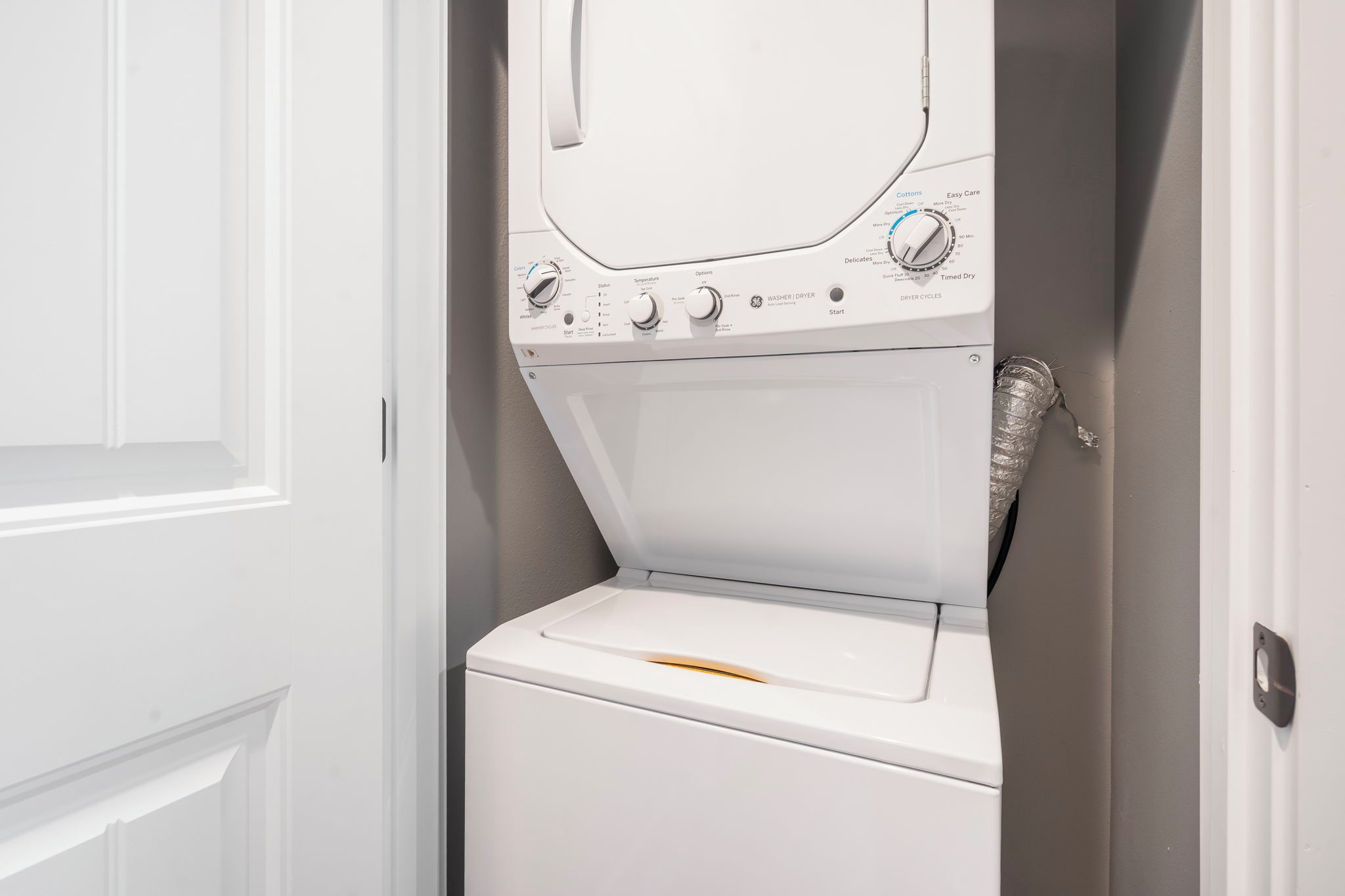 A front view of a white front-loading washing machine with control knobs and a door.