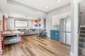 Una cocina moderna con refrigerador integrado, una zona de comedor con mesa y sillas, y una bandera en la pared.