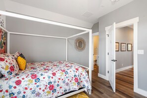 A bedroom with a four-poster bed, a floral bedspread, and a hallway leading to a bathroom. - Panoramic Table Rock Lake Views, Shared Outdoor Pool, Air Hockey, Free Tickets (Branson)