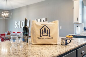 A kitchen counter with a wine bottle, glasses, a coffee mug, and a branded tote bag. - Panoramic Table Rock Lake Views, Shared Outdoor Pool, Air Hockey, Free Tickets (Branson)