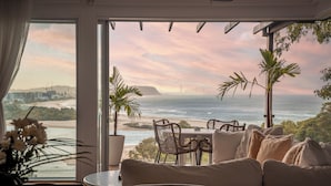 A room with a view of the ocean, a table, and a sofa.