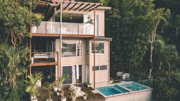 Una moderna casa a più piani con piscina, immersa nel verde.