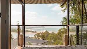 A room with large windows overlooking a beach and ocean, with a patterned rug on the floor.