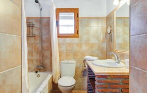 A bathroom with a bathtub, toilet, and sink with a mirror. - Frigiliana villa: 2BR villa, private pool, A/C & dazzling views (Frigiliana)