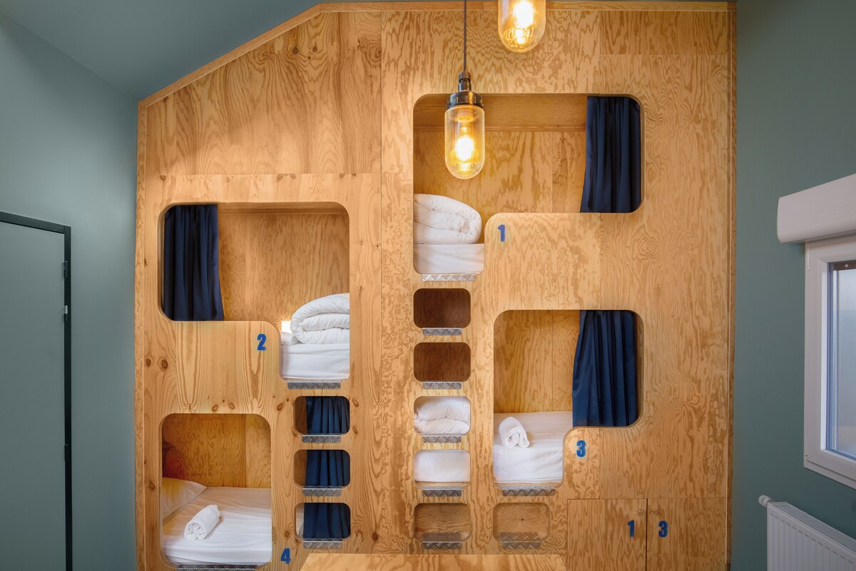A wooden bunk bed room with three levels, numbered 1, 2, and 3, and a hanging light fixture.