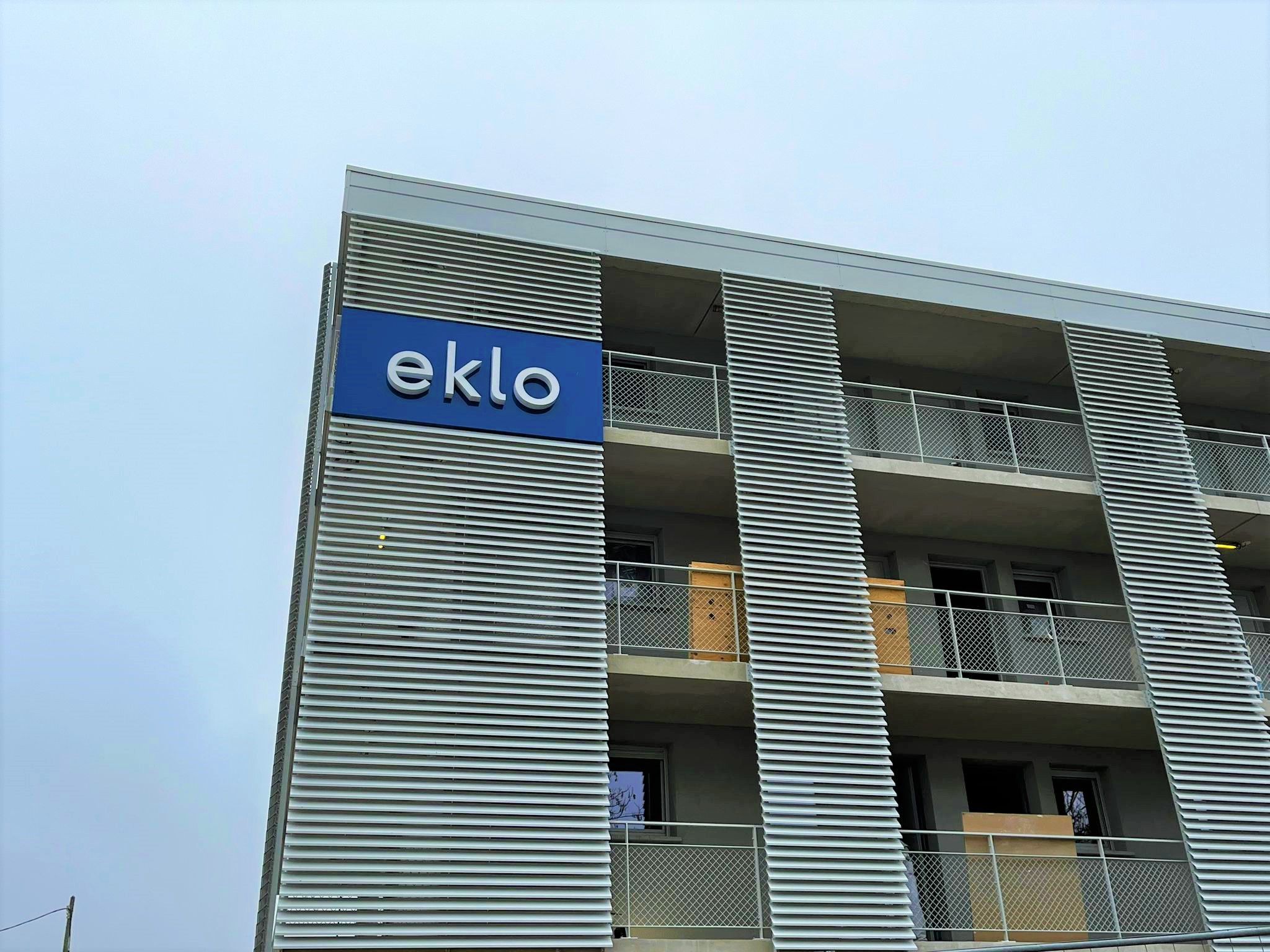 Um edifício com uma placa na fachada que diz 'eklo'.