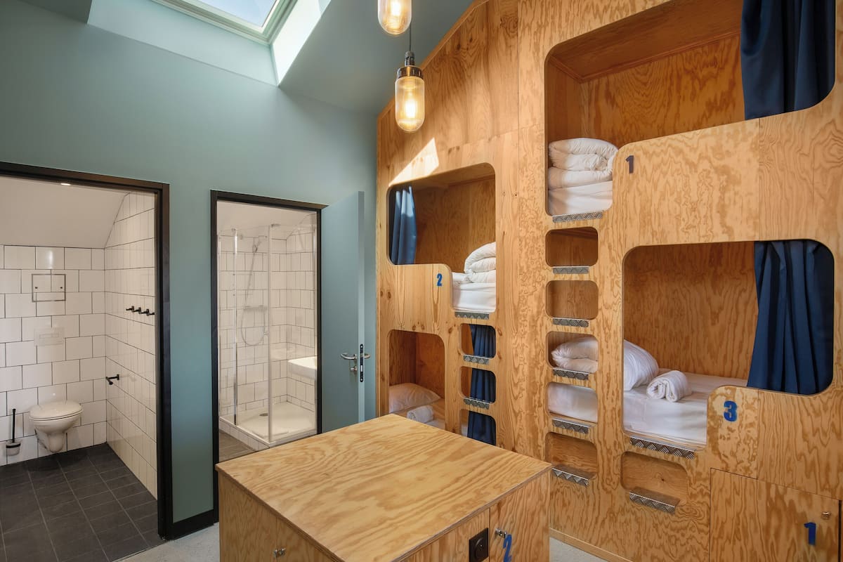 A compact, modern bathroom with a shower, toilet, and a wooden vanity with a mirror.