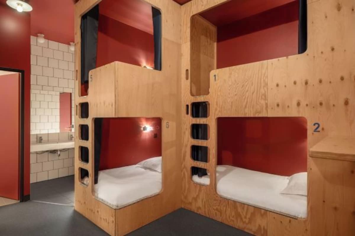 Bunk beds with wooden frames and red accents, a sink, and a tiled wall.