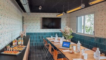 Uma sala de conferências com uma mesa comprida, cadeiras, um laptop e uma tela grande.