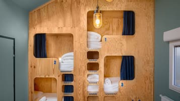 Habitación con literas de madera y compartimentos numerados, cada uno con una toalla enrollada.