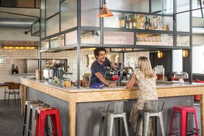 A bar area with stools, a counter, and a bartender.