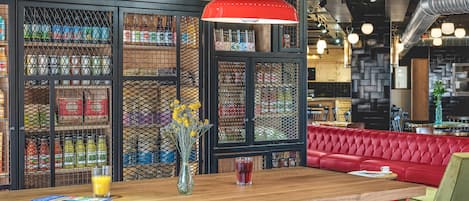 L’intérieur d’un restaurant avec un bar en bois, des sièges rouges et une enseigne décorative au-dessus du bar.