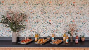 Una encimera de cocina con papel tapiz floral, varios alimentos y botellas.