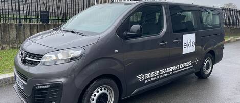A gray van with "ROISSY TRANSPORT EXPRESS" and "eklo" branding parked on a wet road.
