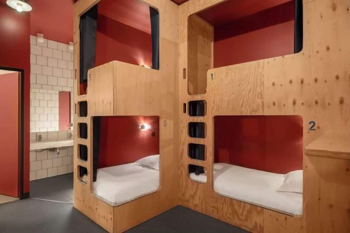 Bunk beds with wooden frames and red accents, a sink, and a tiled wall.