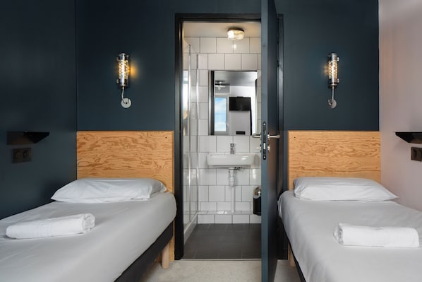 Een hotelkamer met twee bedden, een houten hoofdbord, een wastafel en een spiegel.