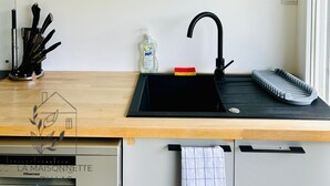Eine Küche mit einem schwarzen Spülbecken, einem Messerblock und einem Geschirrgestell.