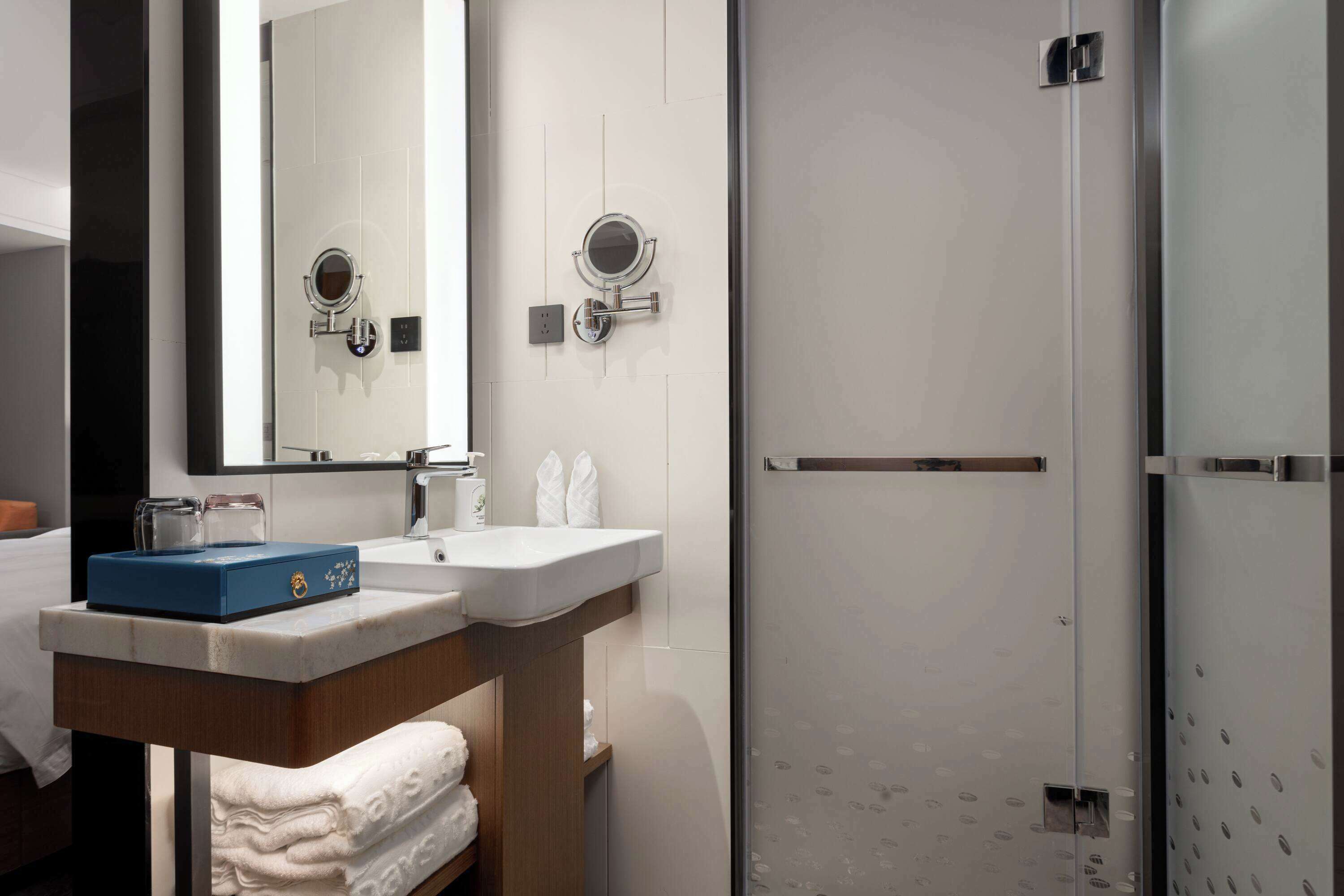 A modern bathroom with a sink, mirror, and a glass shower enclosure.