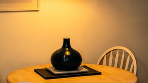 Ein runder Tisch mit einer schwarzen Vase, einem schwarzen Buch und einem weißen Stuhl.