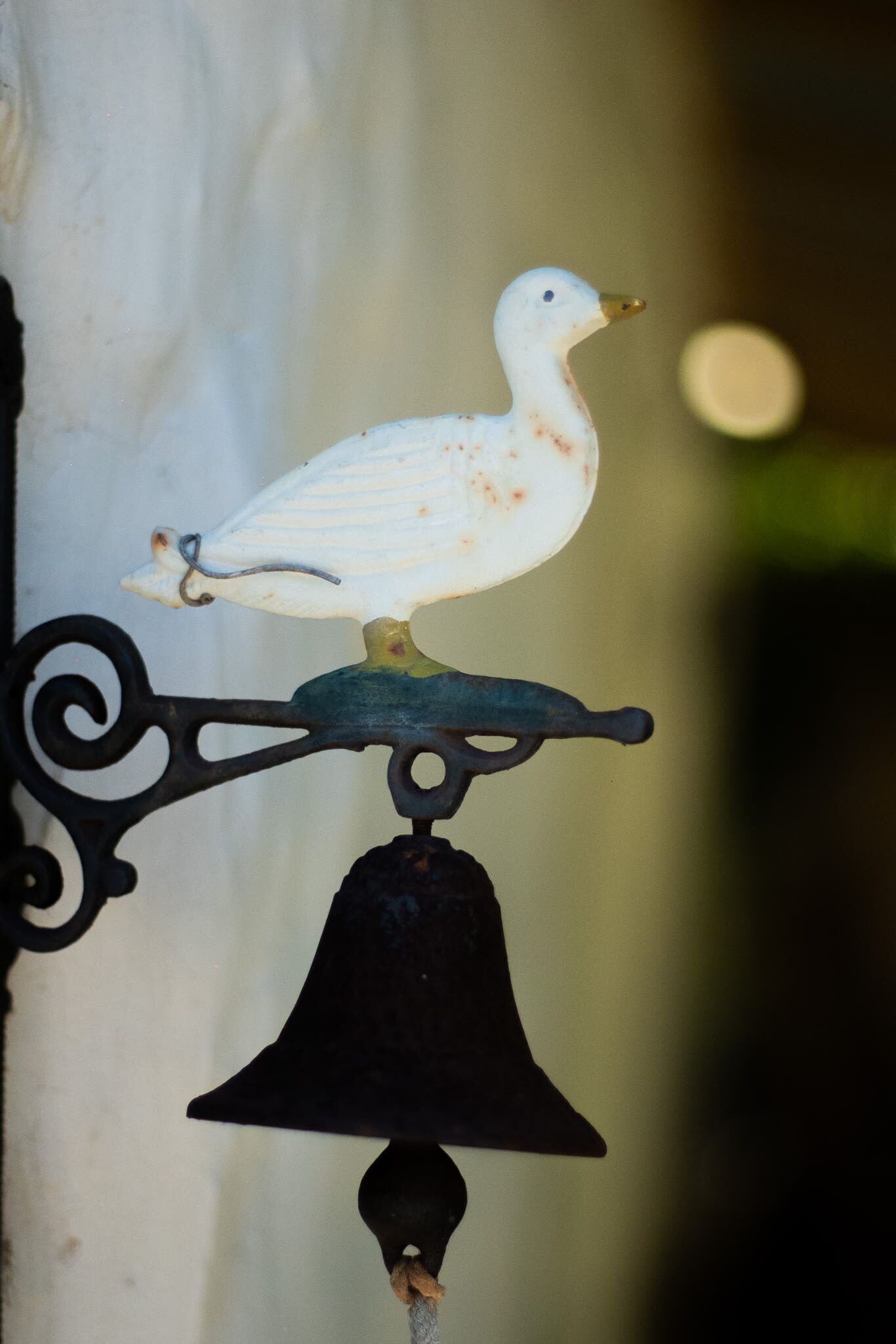 A bird-shaped ornament on a wall-mounted bell.
