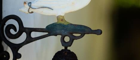A bird-shaped ornament on a wall-mounted bell.