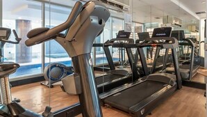 Une salle de sport équipée de tapis de course, de vélos d’appartement et d’un appareil d’aviron.