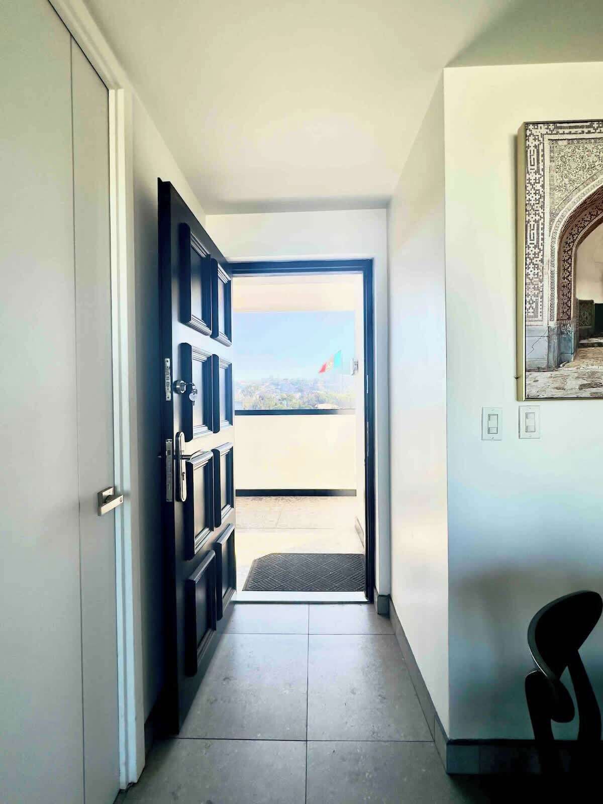 Un pasillo con una puerta que da a un balcón con vistas.