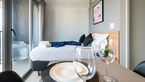 A hotel room with a bed, a glass of wine, and a dining table with a plate and a glass. - Alameda Lorena, 718- Jardim Paulista (São Paulo)