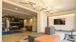 A modern hotel lobby with a dining area, seating arrangements, and a large flat-screen TV. - Alameda Lorena, 718- Jardim Paulista (São Paulo)
