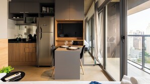 A modern kitchen with a dining area, a refrigerator, and a flat-screen TV. - Alameda Lorena, 718- Jardim Paulista (São Paulo)