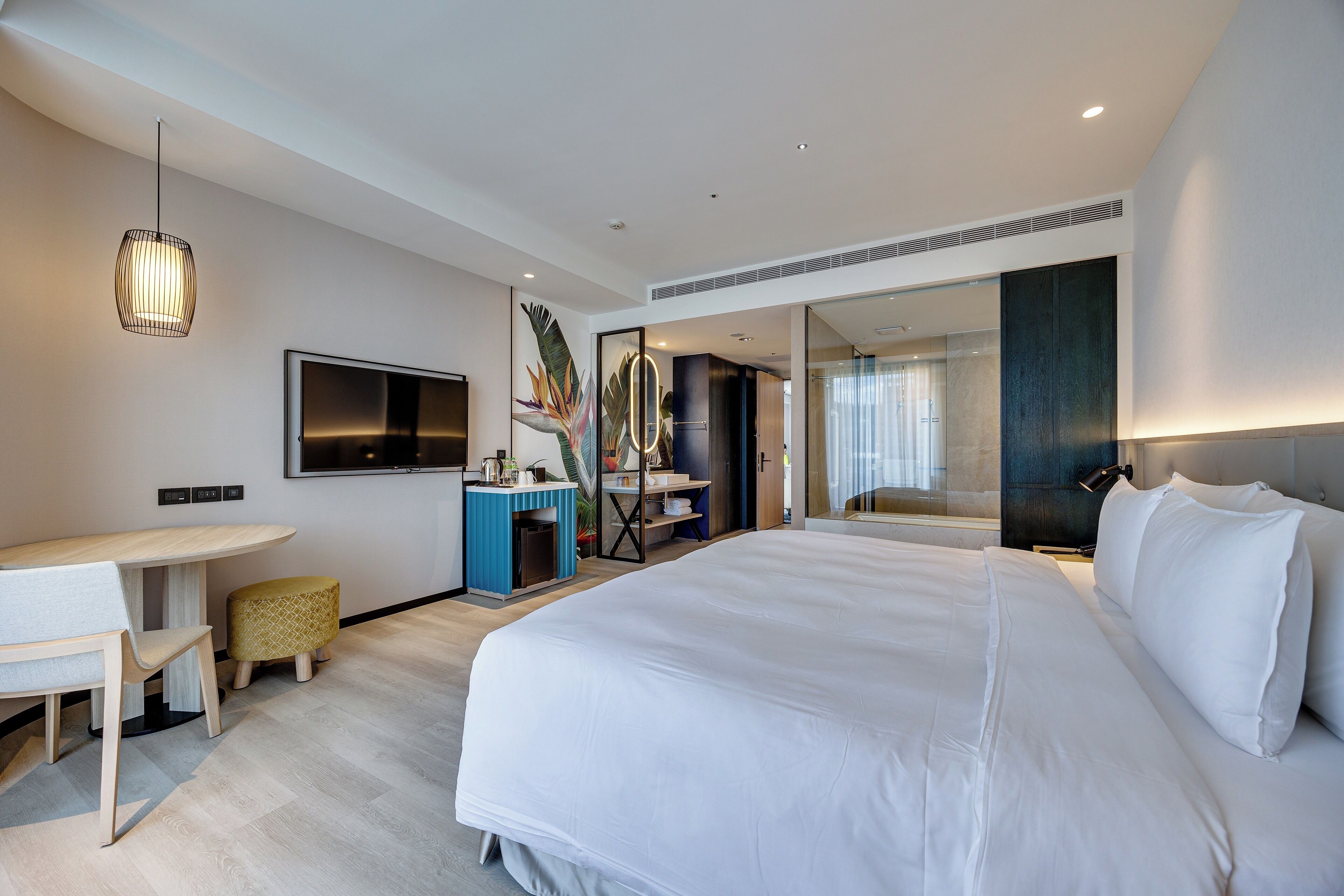 Une chambre d’hôtel moderne avec un grand lit, un bureau et une télévision.