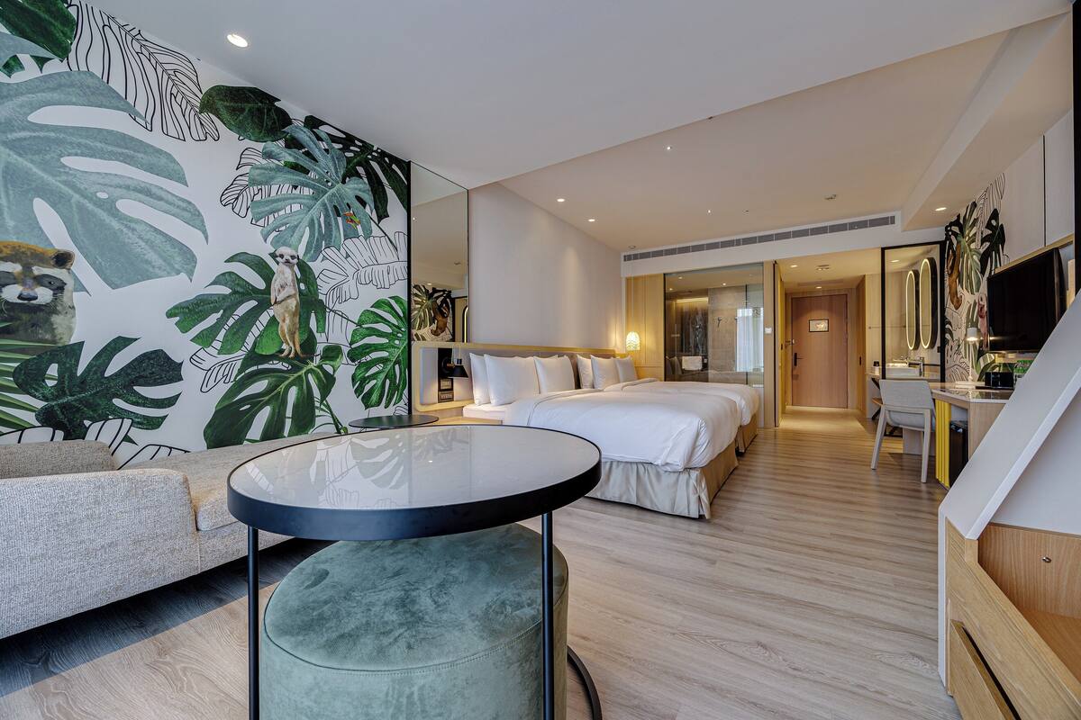 Une chambre d’hôtel moderne avec un grand lit, un canapé, une table ronde et un bureau.