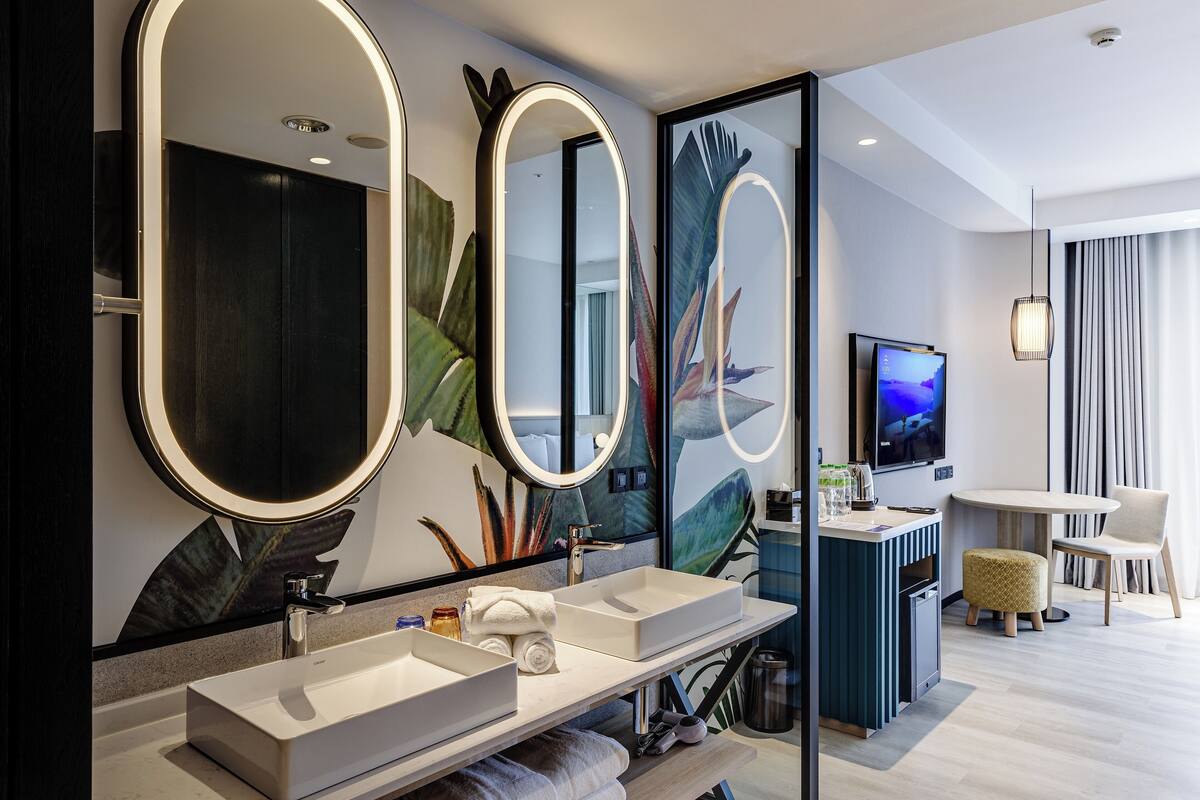 Une salle de bain moderne avec deux lavabos, de grands miroirs et un téléviseur.