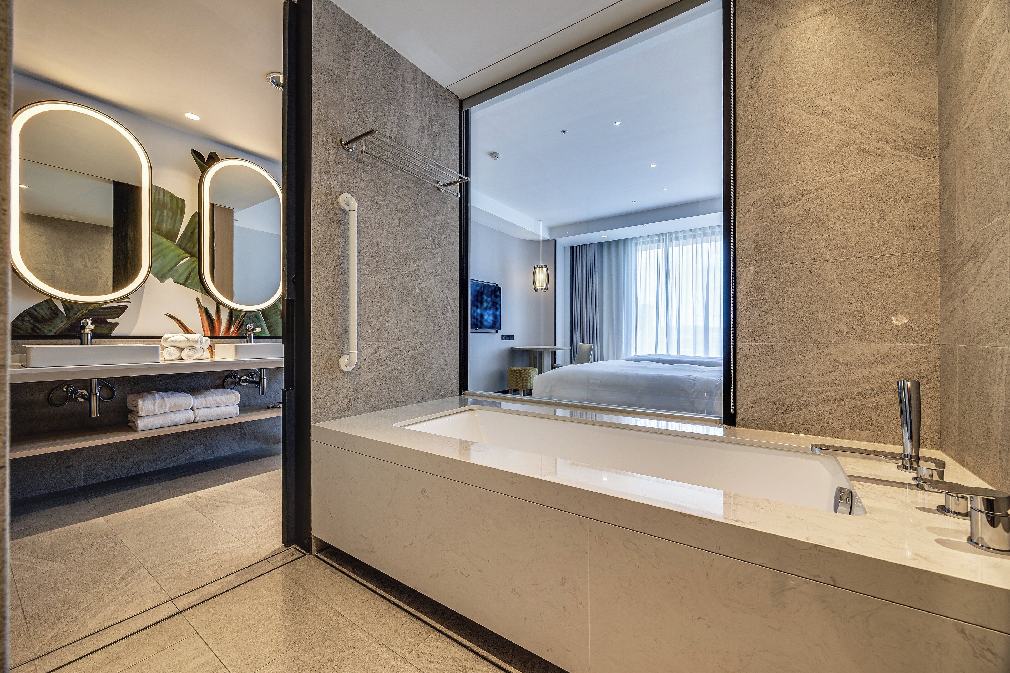 A modern bathroom with a large mirror, a bathtub, and a shower area.