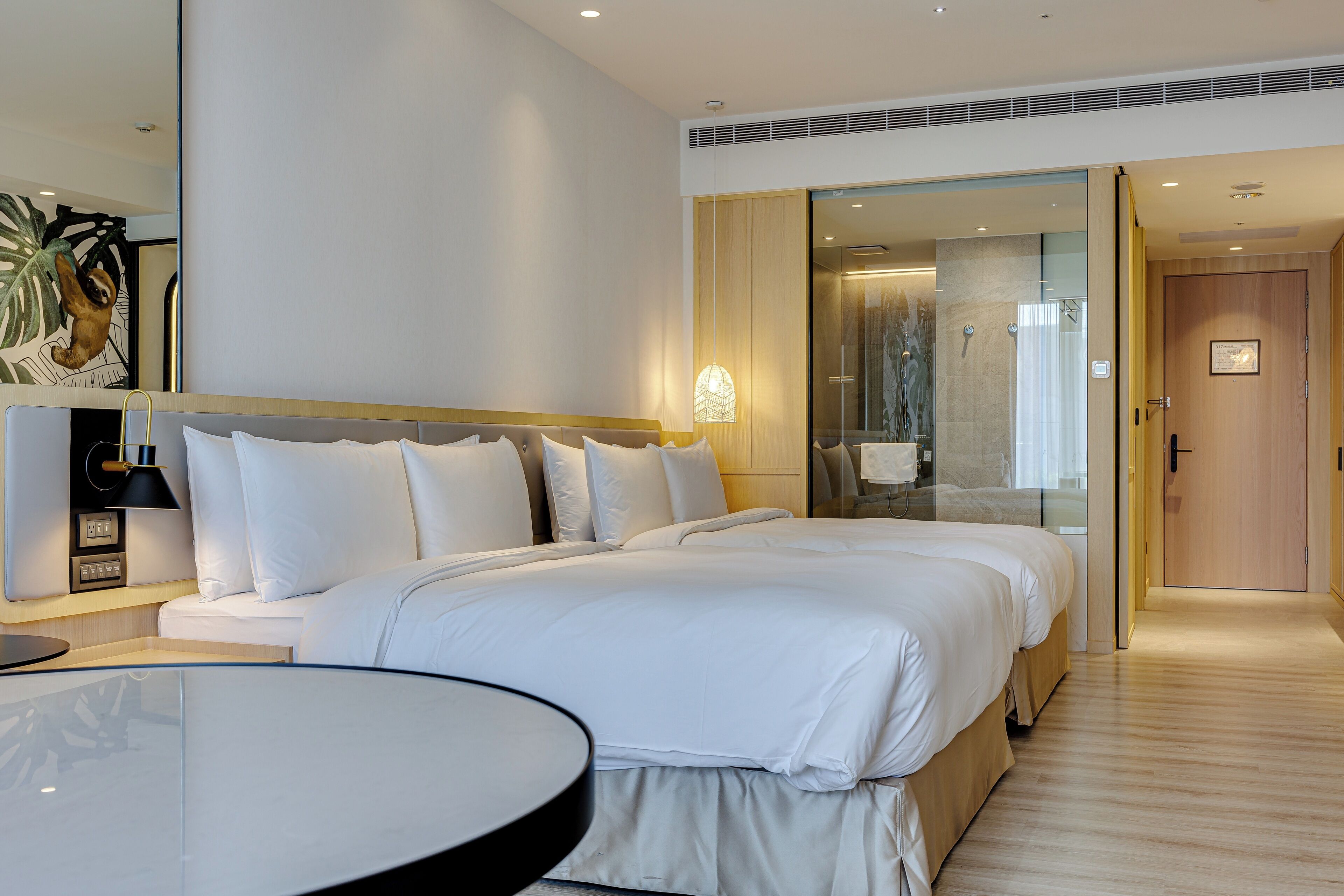 Una habitación de hotel moderna con una cama grande, una mesita de noche, un espejo y vistas al baño.