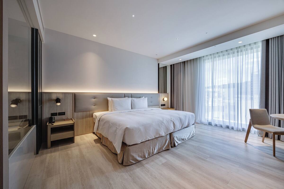 Une chambre d’hôtel moderne avec un grand lit, des tables de chevet, un bureau et une chaise.