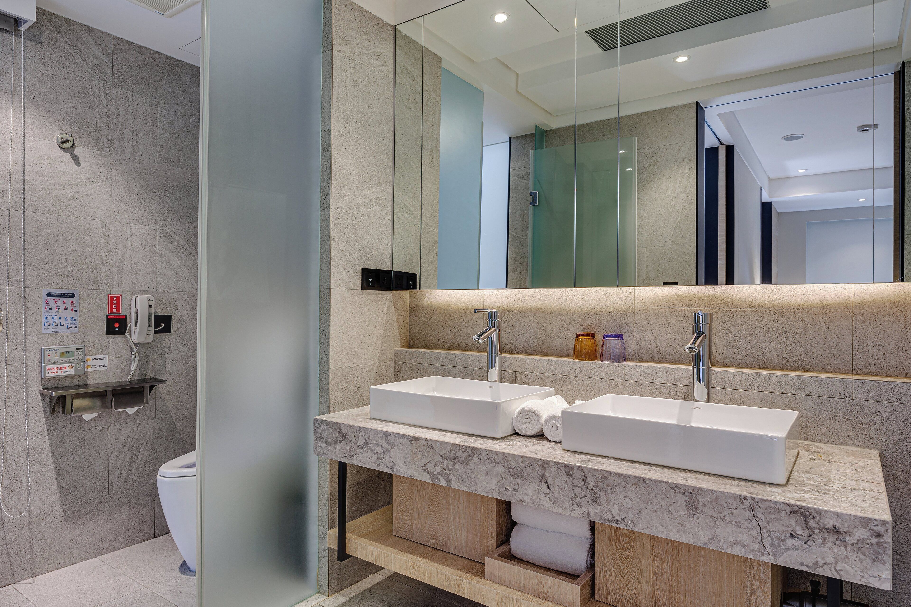 A modern bathroom with two sinks, a toilet, and a glass shower enclosure.