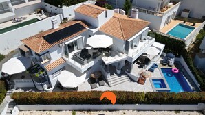 A modern villa with a rooftop terrace, a swimming pool, and a covered outdoor seating area.