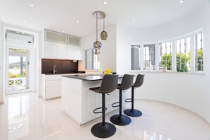 A modern kitchen with a central island, bar stools, and pendant lighting.