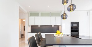 Une cuisine moderne avec des meubles blancs, un plan de travail noir et un coin repas comprenant une table et des chaises.