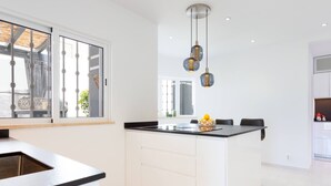 A modern kitchen with a black countertop, white cabinets, and a hanging light fixture.