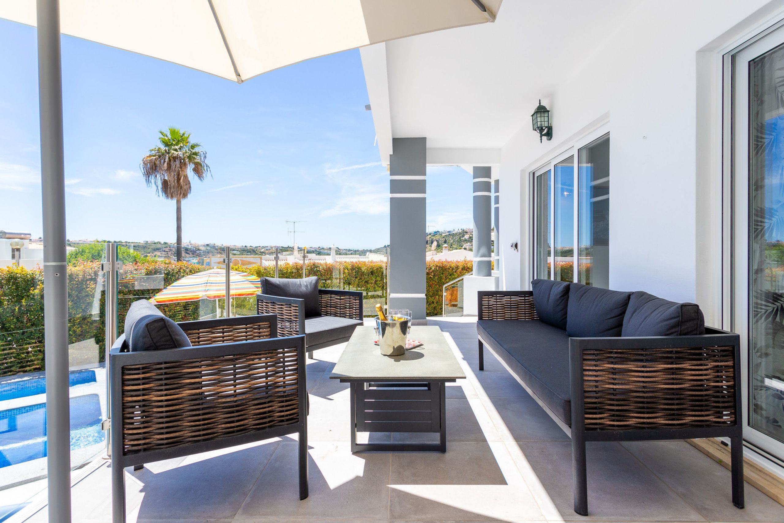 Un espace extérieur moderne, aménagé avec des meubles en osier, une piscine et offrant une vue dégagée sur le paysage environnant.