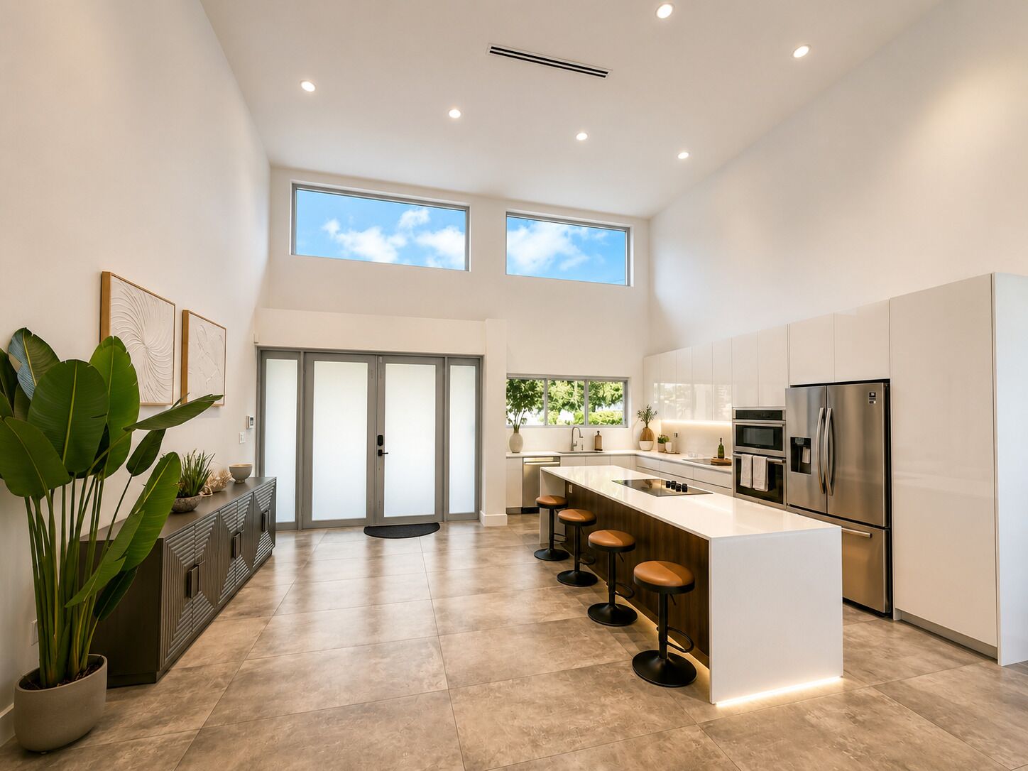 Een moderne keuken met een centraal eiland, barstoelen, een koelkast en een raam met uitzicht op groen.