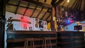 A bar area with wooden stools, a reception desk, and a sign indicating a no-drugs policy. - Puri Raka Villa (Seririt)