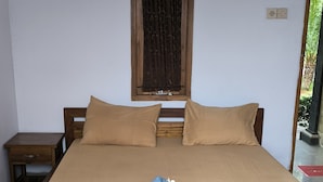 A bedroom with a bed, two pillows, a wooden headboard, a nightstand, a window with curtains, and a door leading outside. - Puri Raka Villa (Seririt)